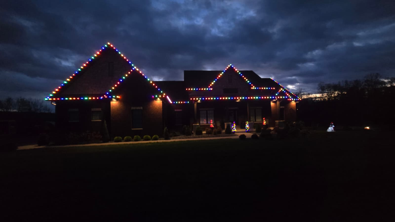 Large brick Southern Indiana home at night lit with C9 Christmas lights along the roofline